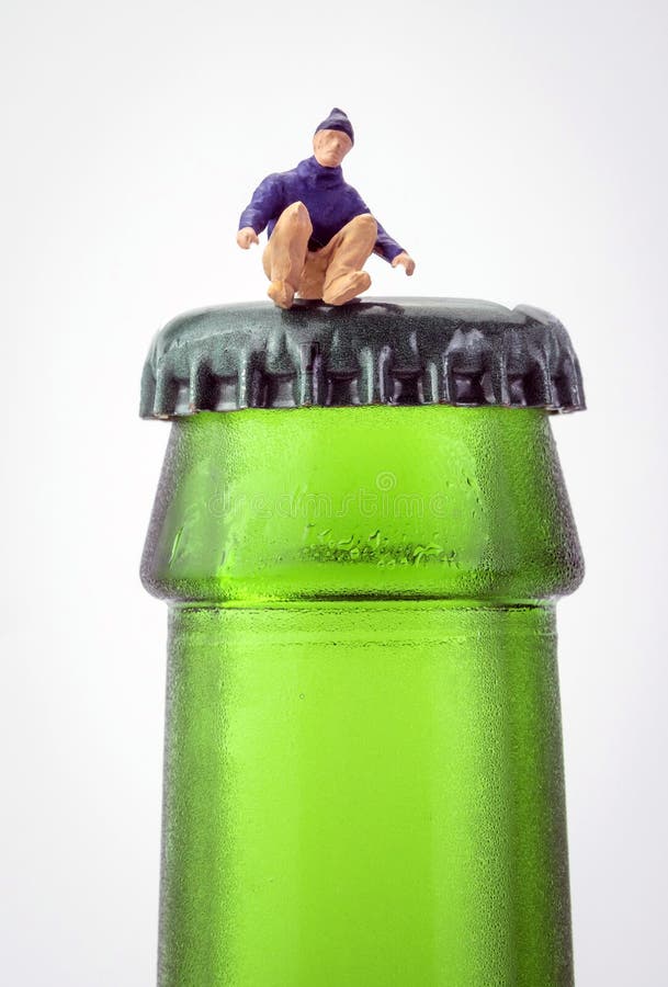 Homme miniature s'asseyant sur une bouteille de bière image stock Homme miniature s'asseyant sur une bouteille de bière image stock