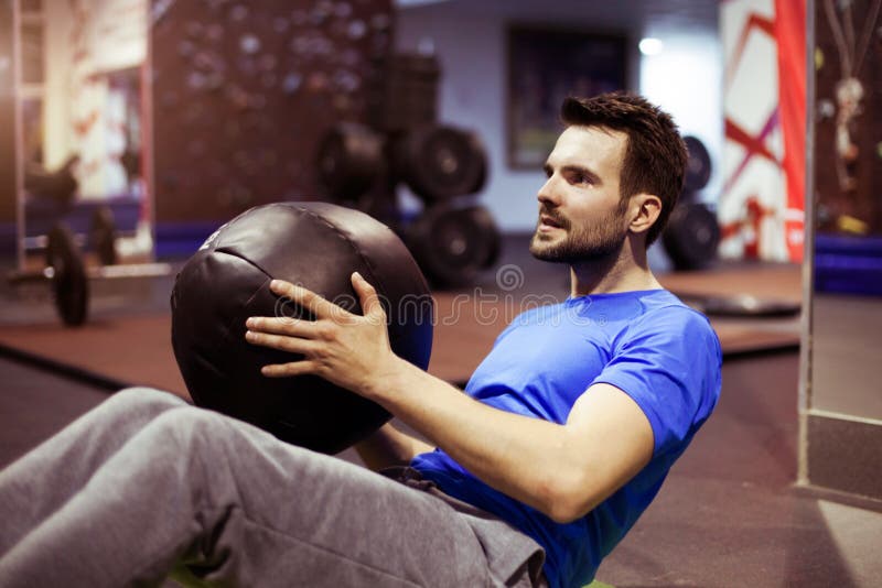 Homme musculaire faisant l'exercice avec le medicine-ball dans le gymnase de crossfit photographie stock Homme musculaire faisant l'exercice avec le medicine-ball dans le gymnase de crossfit photographie stock