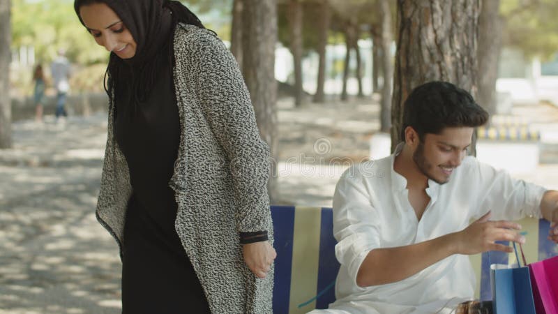 Homme musulman assis sur un banc, femme d'une réunion après avoir fait les courses. clips vidéos