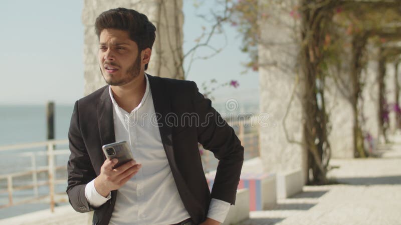 Homme musulman aux cheveux noirs en costume texto message extérieur. banque de vidéos