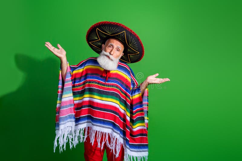 Homme mûr en tenue traditionnelle mexicaine posant avec sombrero et poncho sur fond vert photographie stock