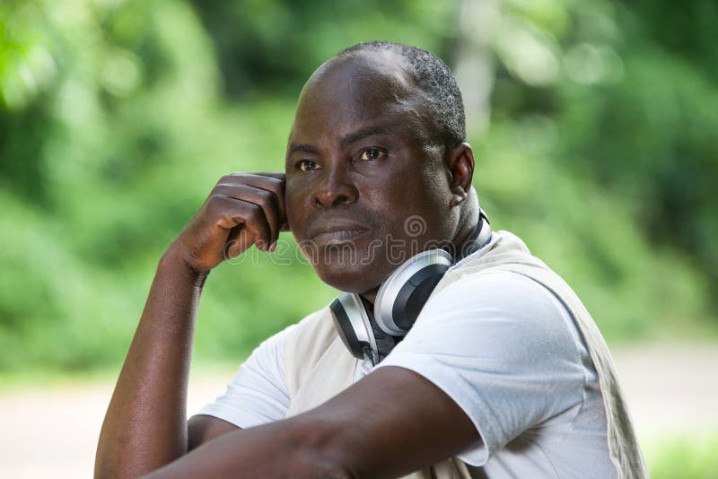 Homme mûr se reposant avec un casque de musique dans la forêt photographie stock libre de droits Homme mûr se reposant avec un casque de musique dans la forêt photographie stock libre de droits