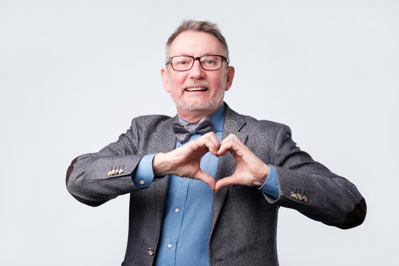 Homme mûr souriant montrant le symbole de coeur avec des mains photos libres de droits Homme mûr souriant montrant le symbole de coeur avec des mains photos libres de droits