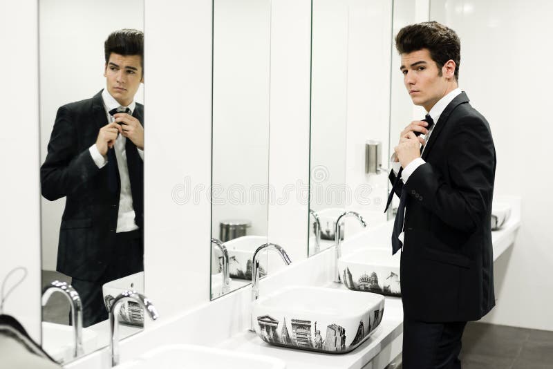 Homme obtenant rectifié dans des toilettes publiques avec le miroir photos stock