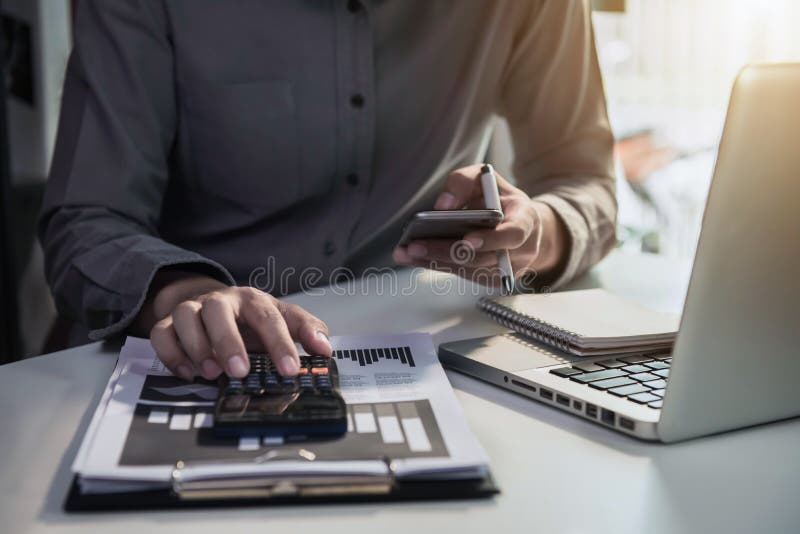 Businessman or accountant working on laptop computer and smartphone with business document, graph diagram and calculator on office table in office. Businessman or accountant working on laptop computer and smartphone with business document, graph diagram and calculator on office table in office.