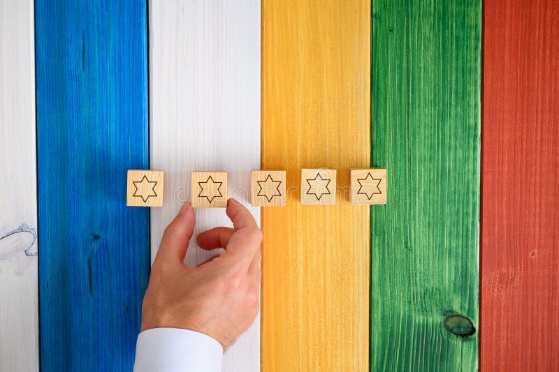 Homme plaçant cinq cubes en bois avec des étoiles sur elles sur le bureau coloré photo stock Homme plaçant cinq cubes en bois avec des étoiles sur elles sur le bureau coloré photo stock