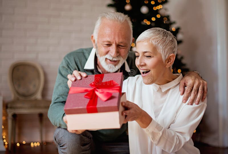 Homme plus âgé donnant un cadeau de Noël à son épouse photo stock Homme plus âgé donnant un cadeau de Noël à son épouse photo stock