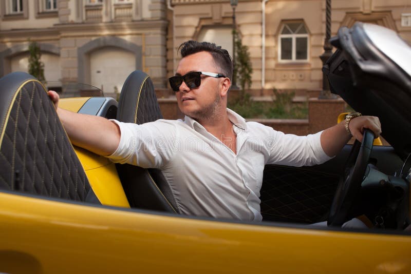 Homme posant avec sportcar convertible photographie stock Homme posant avec sportcar convertible photographie stock