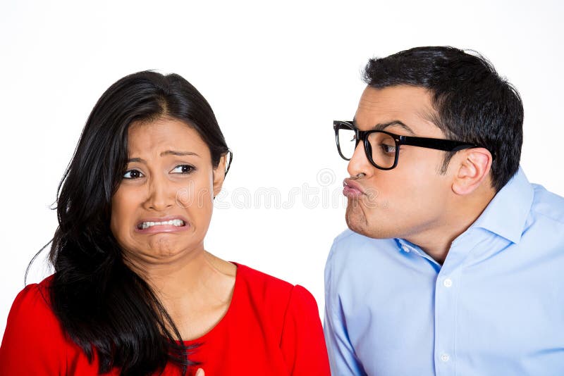 Closeup portrait of nerdy young men with big black glasses trying to kiss snobby women who is grossed out, disgusted funny smirk on face, isolated white background. Negative emotion facial expression. Closeup portrait of nerdy young men with big black glasses trying to kiss snobby women who is grossed out, disgusted funny smirk on face, isolated white background. Negative emotion facial expression