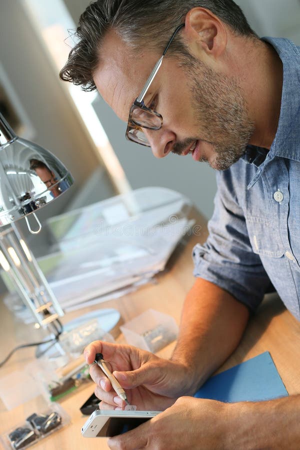 Homme réparant des outils de smartphonewith dans l'atelier images libres de droits Homme réparant des outils de smartphonewith dans l'atelier images libres de droits