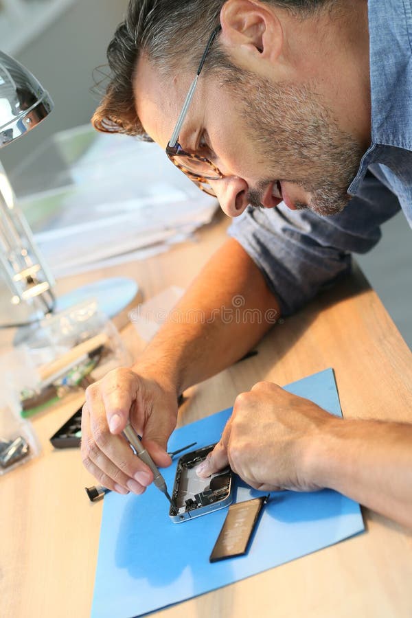 Homme réparant le smartphone dans l'atelier photographie stock Homme réparant le smartphone dans l'atelier photographie stock