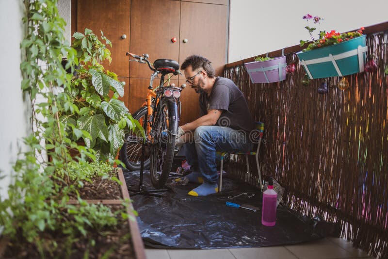 Homme réparant son vélo sur un balcon images libres de droits
