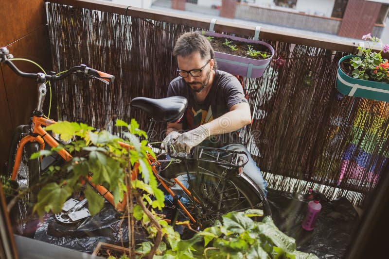 Homme réparant son vélo sur un balcon photo libre de droits