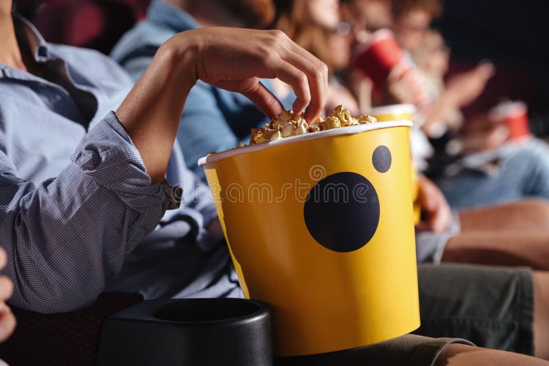 Cropped picture of young men sitting in cinema watch film eating popcorn. Cropped picture of young men sitting in cinema watch film eating popcorn.