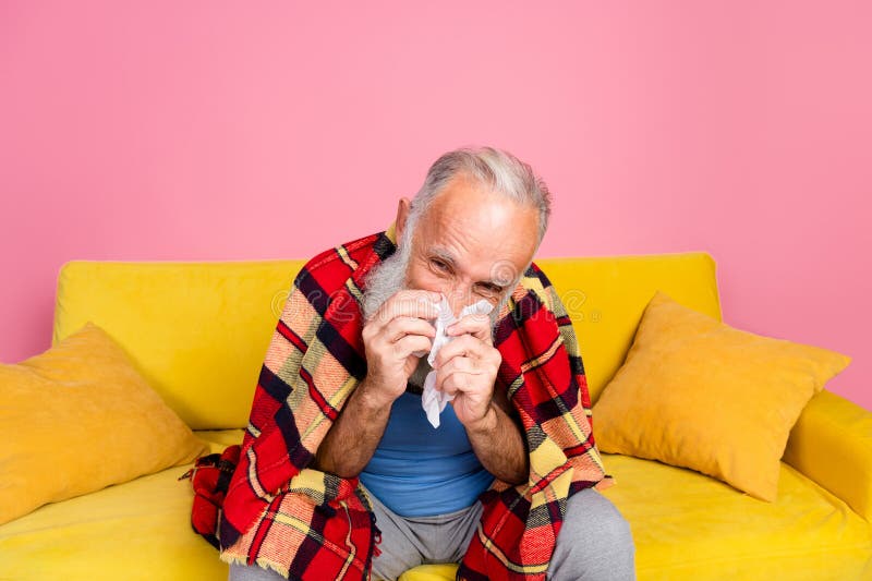 Homme senior avec couverture plaid assise sur un canapé élégant dans la maison colorée photos stock