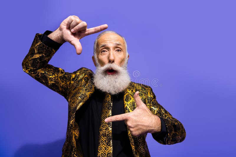 Homme senior excentrique dans un costume stylisé faisant un geste créatif sur fond violet mettant en avant le charisme photo libre de droits