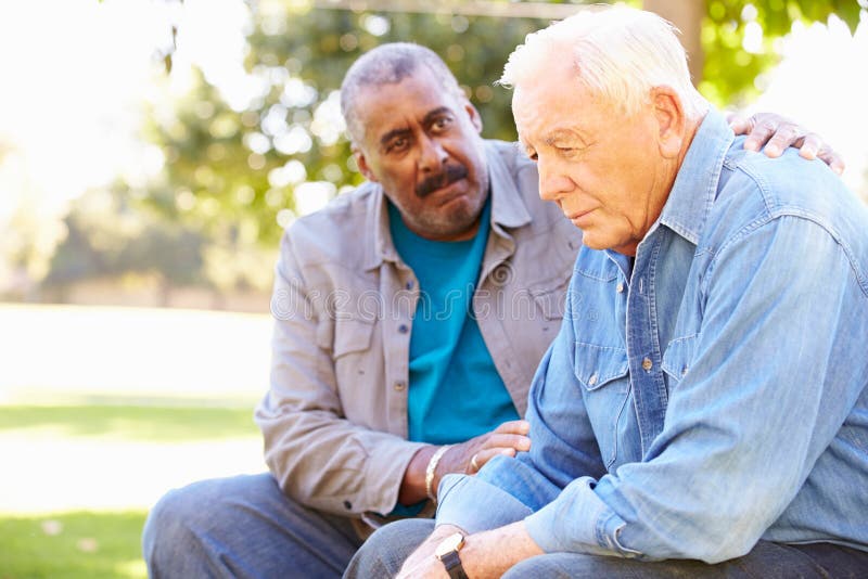 Man Comforting Unhappy Senior Friend Outdoors Putting Hand On Shoulder Looking Concerned. Man Comforting Unhappy Senior Friend Outdoors Putting Hand On Shoulder Looking Concerned