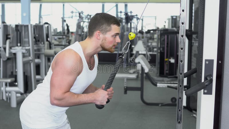 Homme sportif fort dans un T-shirt à la formation de gymnase sur le périphérique en mode bloc Formation de CrossFit image libre de droits Homme sportif fort dans un T-shirt à la formation de gymnase sur le périphérique en mode bloc Formation de CrossFit image libre de droits