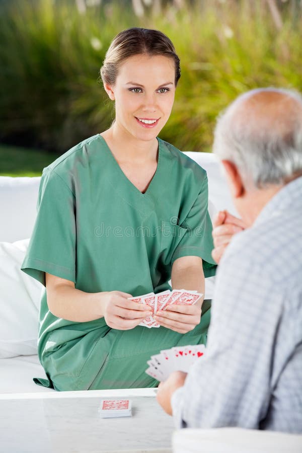 Homme supérieur de Playing Cards With d'infirmière féminine photo stock Homme supérieur de Playing Cards With d'infirmière féminine photo stock