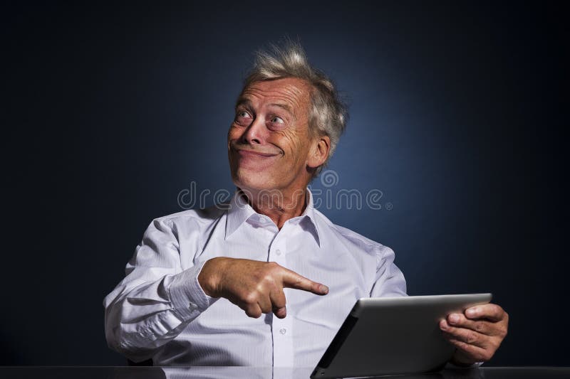 Homme supérieur grimaçant et indiquant son comprimé photographie stock libre de droits Homme supérieur grimaçant et indiquant son comprimé photographie stock libre de droits