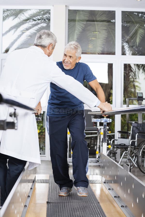 Homme supérieur regardant le centre de réadaptation de docteur While Walking In image stock Homme supérieur regardant le centre de réadaptation de docteur While Walking In image stock
