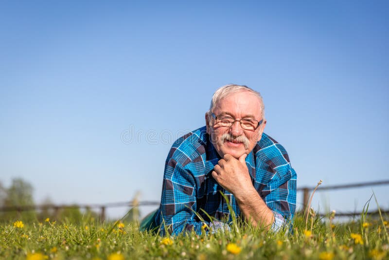 Homme supérieur se trouvant sur le champ d'été dans l'herbe verte images libres de droits Homme supérieur se trouvant sur le champ d'été dans l'herbe verte images libres de droits