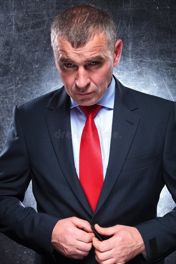 Homme sérieux dramatique d'affaires mûres déboutonnant son manteau photos libres de droits Homme sérieux dramatique d'affaires mûres déboutonnant son manteau photos libres de droits