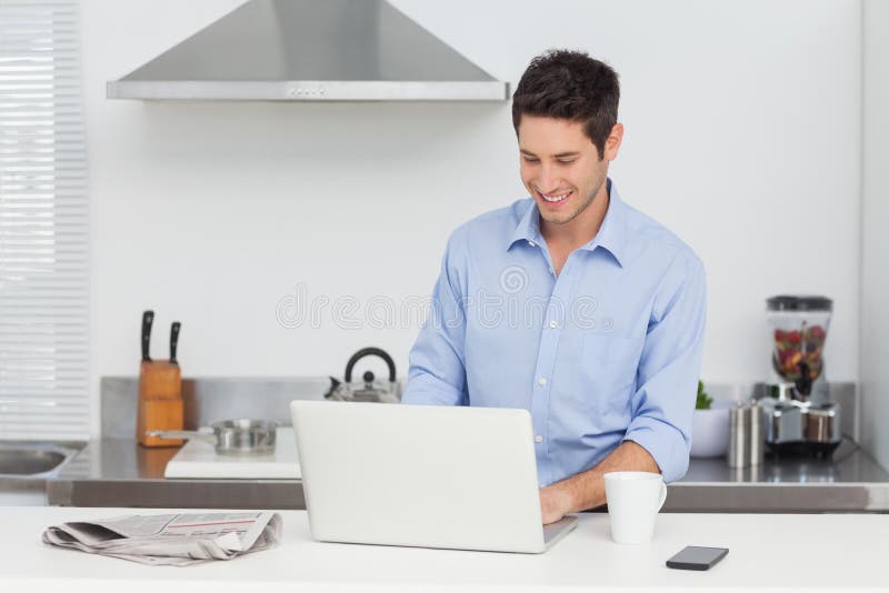 Homme à l'aide d'un PC d'ordinateur portable dans la cuisine photos stock