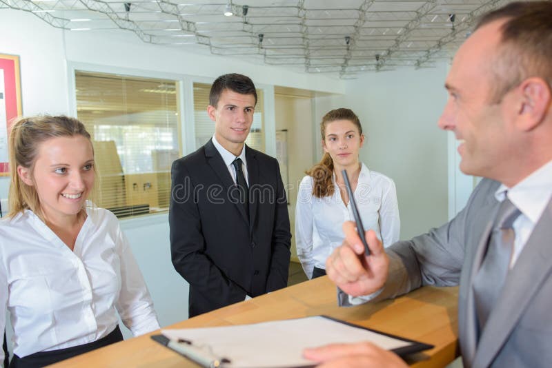 Homme à l'hôtel de réception avec des travailleurs image libre de droits Homme à l'hôtel de réception avec des travailleurs image libre de droits