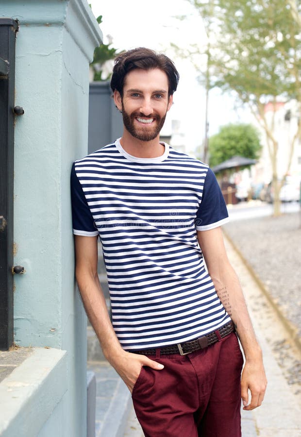 Homme à la mode heureux dans la chemise rayée se penchant contre le mur dehors images libres de droits Homme à la mode heureux dans la chemise rayée se penchant contre le mur dehors images libres de droits