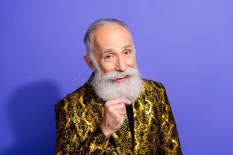 Homme âgé excentrique avec un costume doré élégant posant avec confiance sur un fond violet vibrant photo libre de droits
