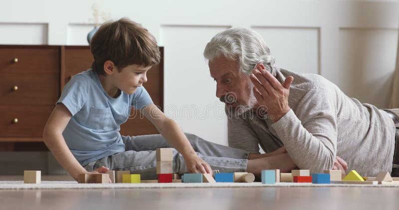 Homme âgé moyen heureux en jouant avec le petit-fils à la maison. banque de vidéos