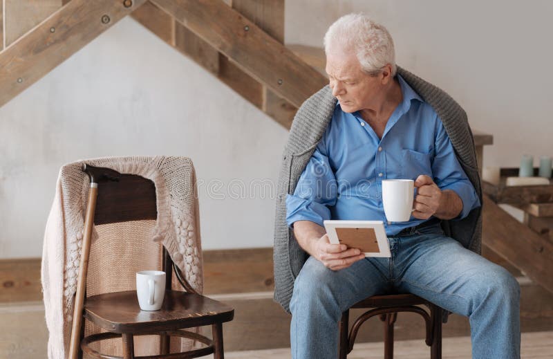 Homme âgé sombre regardant la chaise près de lui image libre de droits
