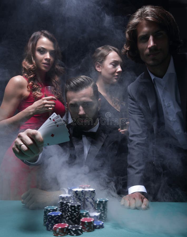 Hommes concentrés et femmes jouant le tisonnier dans le casino photo stock Hommes concentrés et femmes jouant le tisonnier dans le casino photo stock