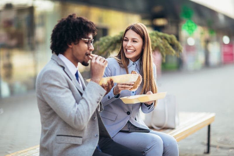 Hommes d'affaires avec des sandwichs se reposant devant l'immeuble de bureaux - pause de midi photos stock Hommes d'affaires avec des sandwichs se reposant devant l'immeuble de bureaux - pause de midi photos stock