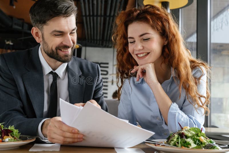 Hommes d'affaires ayant le déjeuner d'affaires à la consommation se reposante de restaurant discutant le contrat gai image libre de droits Hommes d'affaires ayant le déjeuner d'affaires à la consommation se reposante de restaurant discutant le contrat gai image libre de droits