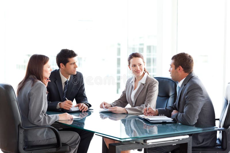 Hommes d'affaires et femmes d'affaires parlant à une table photographie stock libre de droits Hommes d'affaires et femmes d'affaires parlant à une table photographie stock libre de droits