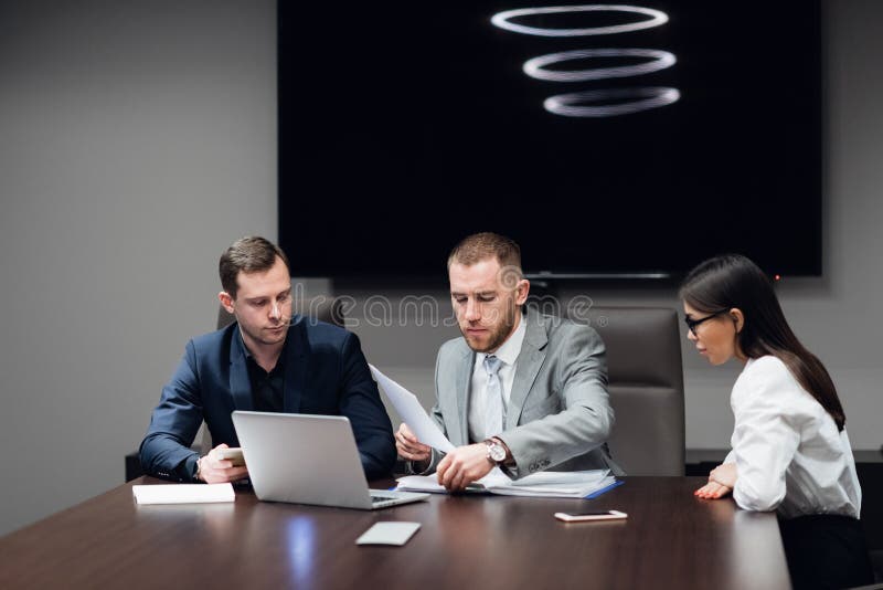 Hommes d'affaires travaillant ensemble sur leur ordinateur portable dans un lieu de réunion image stock Hommes d'affaires travaillant ensemble sur leur ordinateur portable dans un lieu de réunion image stock