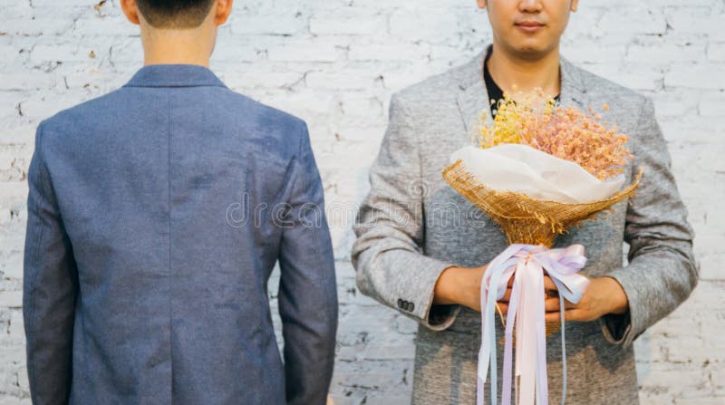 Homoseksualna para trzyma bukiet kwiaty, przygotowywającego dawać jego partner dla specjalnych okazj lub ślub propozyci fotografia stock Homoseksualna para trzyma bukiet kwiaty, przygotowywającego dawać jego partner dla specjalnych okazj lub ślub propozyci fotografia stock