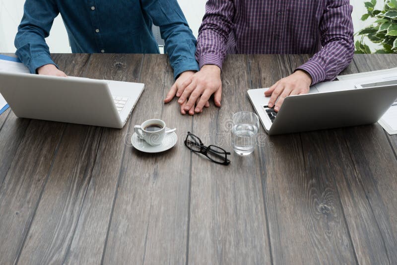 Homosexual partners working together at office desk, they are holding hands, love and relationships concept. Homosexual partners working together at office desk, they are holding hands, love and relationships concept