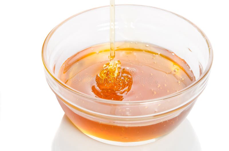 Honey Dripping from a Wooden Honey Dipper into Glass Bowl Stock Image