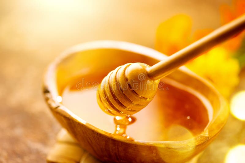 Honey dripping from honey dipper in wooden bowl. Close-up. Healthy organic Thick honey dipping from the wooden honey spoon stock photography Honey dripping from honey dipper in wooden bowl. Close-up. Healthy organic Thick honey dipping from the wooden honey spoon stock photography