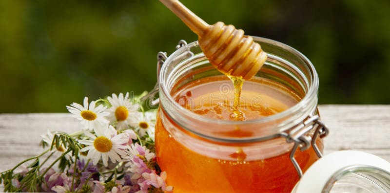 Honey in Glass Jar with Bee Flying and Flowers on a Wooden Floor Stock ...