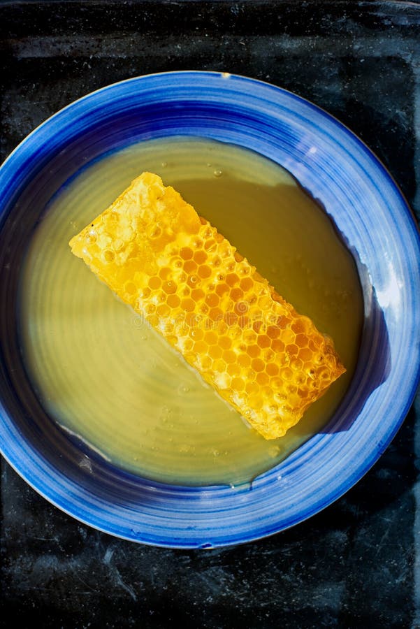 Honeycomb piece with honey on a blue plate stock images Honeycomb piece with honey on a blue plate stock images