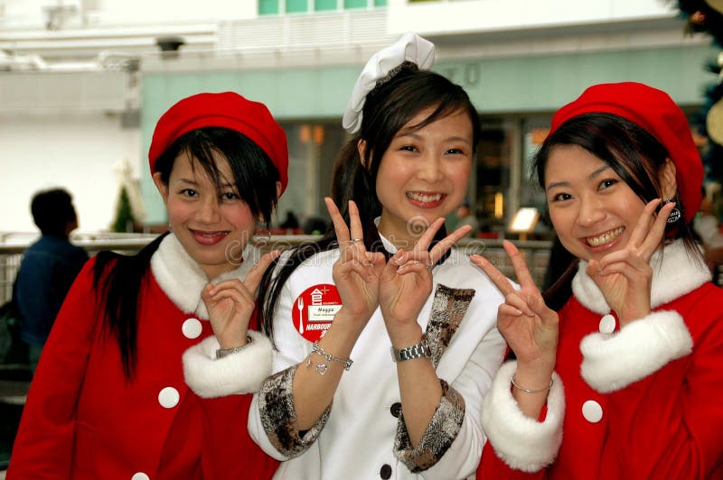 Hong Kong, China: Three young Asian women dressed in Christmas holiday outfits welcome shoppers to the Harbour City shopping complex in Kowloon. Hong Kong, China: Three young Asian women dressed in Christmas holiday outfits welcome shoppers to the Harbour City shopping complex in Kowloon