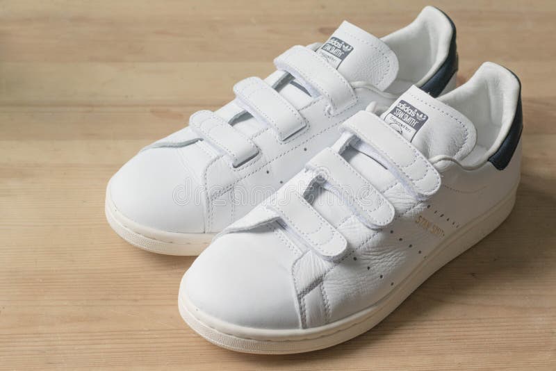 Hong Kong, Cina - 6 luglio 2016: Bianco di originali di Adidas e marina Stan Smith Velcro Trainers su una superficie di legno fotografia stock libera da diritti Hong Kong, Cina - 6 luglio 2016: Bianco di originali di Adidas e marina Stan Smith Velcro Trainers su una superficie di legno fotografia stock libera da diritti