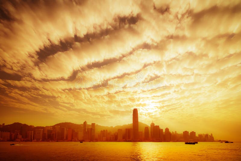 Hong Kong skyline in golden dusk with dramatic clouds