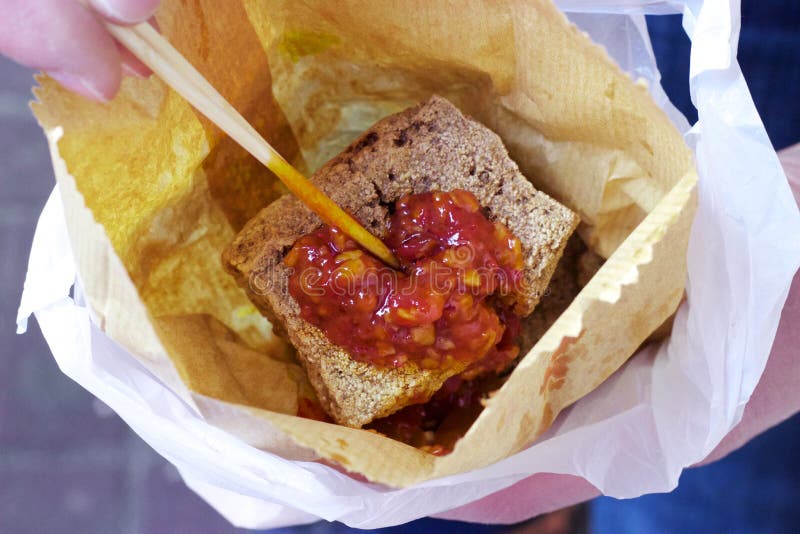 Hong Kong street food: Stinky tofu, chili sauce, paper bag. Stinky or smelly tofu, a fermented tofu, is a classic street food. Here in Hong Kong, it`s shown stock photos Hong Kong street food: Stinky tofu, chili sauce, paper bag. Stinky or smelly tofu, a fermented tofu, is a classic street food. Here in Hong Kong, it`s shown stock photos