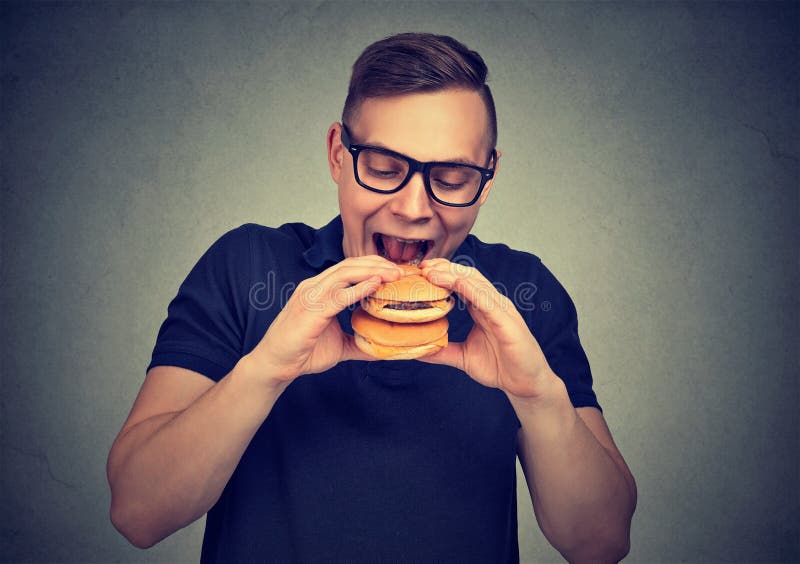 Hongerige mens die dubbele hamburger hebben stock afbeeldingen Hongerige mens die dubbele hamburger hebben stock afbeeldingen