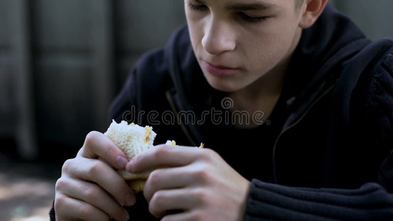 Hongerige tienerjongen die goedkope ongezonde sandwich, slechte kwaliteitsmaaltijd voor kind eten stock afbeelding Hongerige tienerjongen die goedkope ongezonde sandwich, slechte kwaliteitsmaaltijd voor kind eten stock afbeelding
